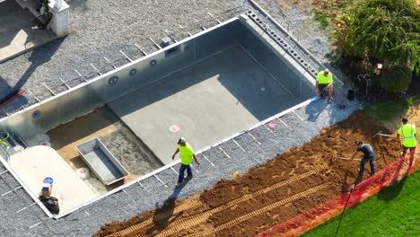 Arbeiter-Bauen-Einen-Pool,-Legen-Kies-Und-Fundament,-Mit-Sicherheitsausrüstung