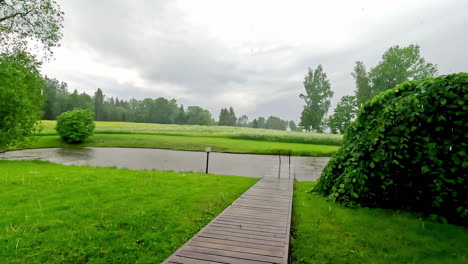Calming-light-rain-outdoor-in-green-rural-landscape-with-tree-and-wooden-deck