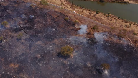 Aerial-view-overlooking-helicopter-firefighting-forest-fire-natural-disaster-on-dry-grass-smoky-hillside