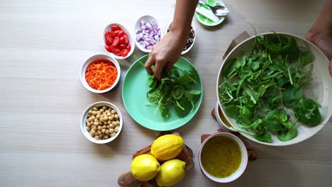 Adding-spinach-leaves-to-plate-aerial-view-of-all-ingredients-on-the-table