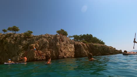 Croatia,-Krk,-Stara-Baška,-Zala-Beach-kids-are-climbing-and-jumping-into-the-sea-from-the-edge-of-the-cliff