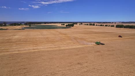 High-shot-of-a-harvester-working-in-a-paddock-with-Lake-Mulwala-and-paddocks-beyond
