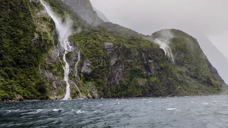 Tourist-perspective-shot-of-waterfall-flowing-down-the-cliffs-in-heavy-wind