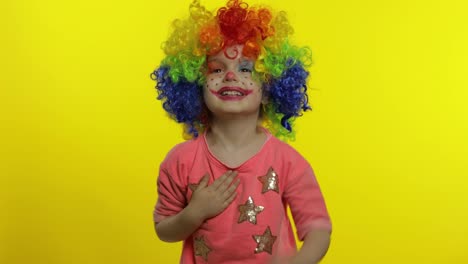 Little-child-girl-clown-in-colorful-wig-tells-something-interesting.-Having-fun,-smiling.-Halloween