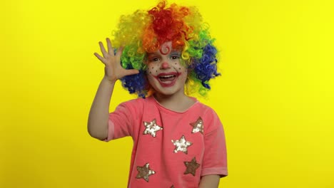 Little-child-girl-clown-in-colorful-wig-making-silly-faces.-Shows-ok-sign,-smiling.-Halloween