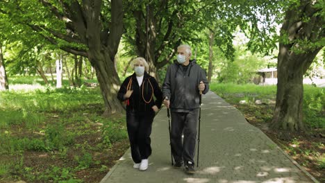 Active-senior-old-man,-woman-training-Nordic-walking-in-park-during-quarantine