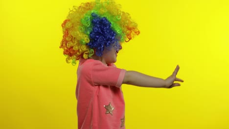 Little-child-girl-clown-in-colorful-wig-waving-hands,-having-fun,-smiling.-Halloween