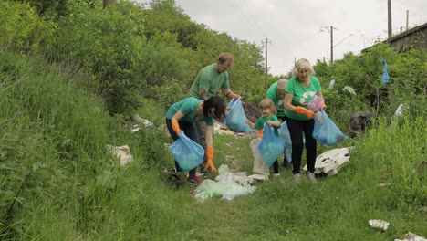 Team-of-nature-activists-in-eco-T-shirts-picking-up-plastic-trash-in-park.-Recycle,-earth-pollution