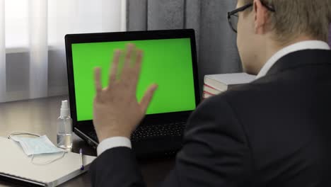 Man-have-video-call-conference-on-laptop-with-green-screen.-Distance-work-online