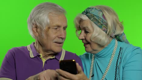 Mature-senior-old-couple-grandparents-enjoy-online-shopping-on-mobile-phone