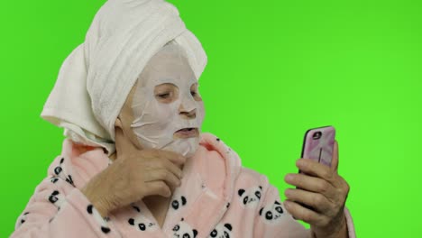 Großmutter-Im-Bademantel,-Gesichtsmaske.-Alte-Frau-Nutzt-Mobiltelefon-Für-Videoanruf