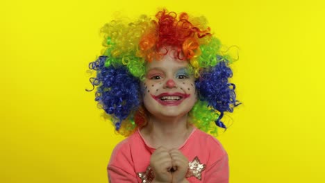 Little-child-girl-clown-in-rainbow-wig-making-silly-faces,-having-fun,-laughing,-dancing.-Halloween