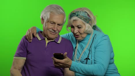Mature-senior-old-couple-grandparents-enjoy-online-shopping-on-mobile-phone