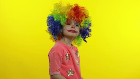 Little-child-girl-clown-in-rainbow-wig-waving-hands,-having-fun,-smiling.-Halloween