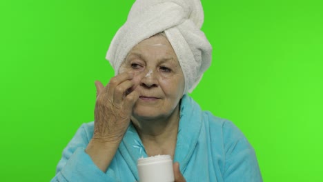 Abuela-Anciana-En-Bata-De-Baño.-Anciana-Aplicando-Crema-Hidratante-En-La-Cara.