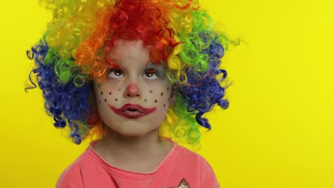 Little-child-girl-clown-in-colorful-wig-tells-something-interesting,-having-fun,-smiling.-Halloween