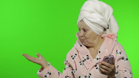 Elderly-grandmother-in-bathrobe.-Old-woman-with-smartphone-pointing-at-something