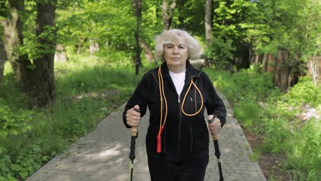 Aktive-ältere-Frau-Trainiert-Nordic-Walking-Mit-Ski-Trekkingstöcken-Im-Park