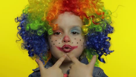 Little-child-girl-clown-in-wig-making-silly-faces,-fool-around,-shows-pistols-with-hands.-Halloween