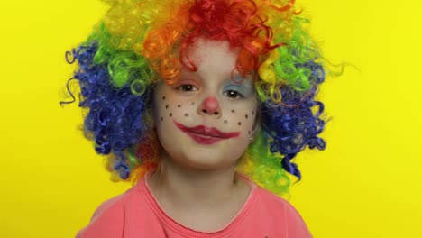 Little-child-girl-clown-in-colorful-wig-tells-something-interesting.-Having-fun,-smiling.-Halloween