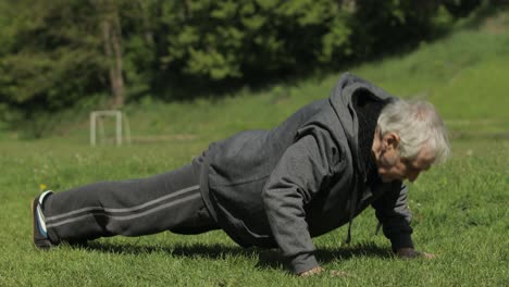 Active-senior-old-man-do-push-ups-physical-exercises-in-sport-playground