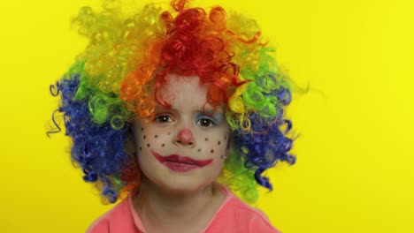 Little-child-girl-clown-in-rainbow-wig-tells-something-interesting.-Having-fun,-smiling.-Halloween