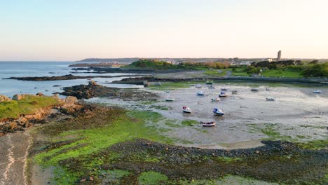 Entrance-to-Bordeaux-Harbour-Guernsey-low-flying-away-at-low-tide-with-boats-drying-on-sandy-bottom-and-green-seaweed-on-foreshore-on-bright-late-afternoon