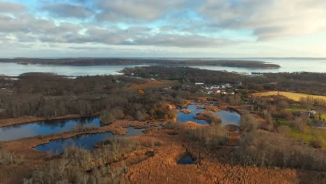 An-aerial-view-over-a-salt-marsh-in-Greenport,-NY-by-the-Long-Island-Sound-on-a-beautiful-day-with-blue-skies-and-white-clouds