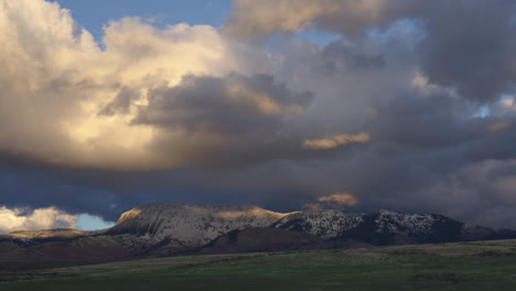Düsterer-Himmel-Mit-Sonnenuntergangswolken,-Die-über-Schneebedeckte-Felsberge-Kriechen