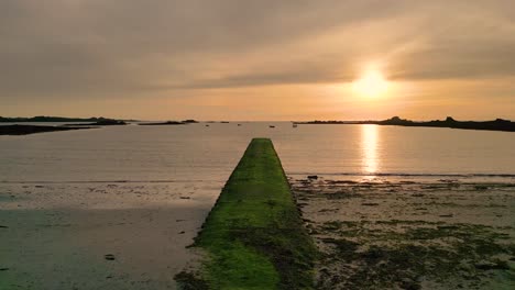 Sonnenuntergang-über-Cobo-Bay-Guernsey-Langsamer-Flug-über-Steg-Und-Strand-Bei-Mittlerer-Flut-In-Den-Sonnenuntergang-Mit-Booten-Vor-Anker-Und-Goldenem-Himmel