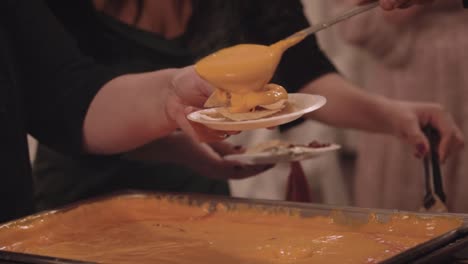 Gooey-Hot-Steamy-Cheese-Being-Scooped-Onto-Plate-Of-Nacho-Chips-At-Buffet