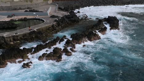 volcanic-pools-of-Porto-Moniz-in-Madeira-Potrugal-fottage-with-drone-of-cliffs,-ocean,-atural-bathing-spots,-houses-filmed-at-sunset
