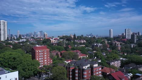 Aerial-reveal-of-Sydney-Skyline-from-Eastern-Suburbs-featuring-Harbor-Bridge-Opera-House,-Darling-Point-and-Rushcutters-Bay-with-sunny-summer-weather-and-blue-sky