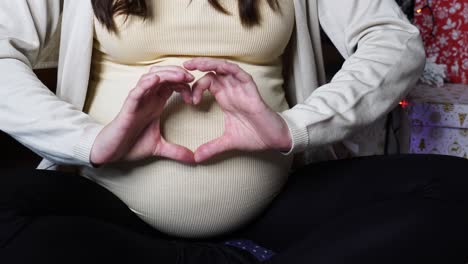 Schwangere-Frau-Formt-Mit-Handflächenfingern-In-Der-Nähe-Von-Weihnachtsgeschenken-Ein-Herz