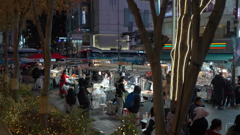 Myeongdong-Night-Market---people-eat-food-from-street-stalls---wide-angle