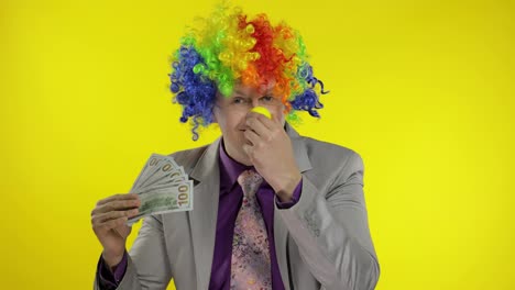 Clown-businessman-entrepreneur-boss-in-wig-waves-with-money-banknotes.-Halloween