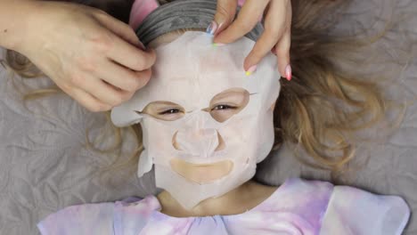 Teenager-Mädchen-Mutter-Trägt-Feuchtigkeitsspendende-Gesichtsmaske-Auf-Tochter-Auf.-Kind-Mit-Kosmetischer-Gesichtshautmaske