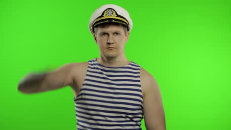 Young-sailor-man-salutes-with-hand-to-camera.-Seaman-guy-in-sailor's-vest