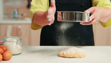 Sifting-flour-on-dough-using-metallic-sieve