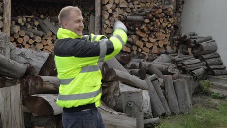 Lumberjack-in-reflective-jacket.-Man-woodcutter-dancing,-celebrate.-Sawn-logs,-firewood-background