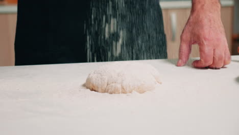 Hands-of-cook-sprinkling-flour-on-dough