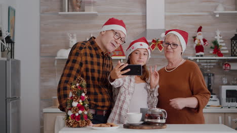 Glückliche-Großeltern-Stehen-Am-Tisch-In-Der-Weihnachtlich-Dekorierten-Küche-Und-Machen-Ein-Selfie-Mit-Smartpgone