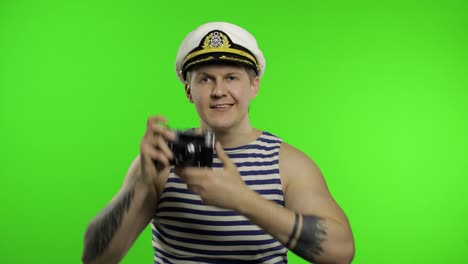 Young-sailor-man-takes-a-photo-on-a-retro-camera.-Seaman-guy-in-sailor's-vest