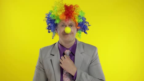Clown-businessman-entrepreneur-boss-in-wig-show-thumb-up.-Yellow-background