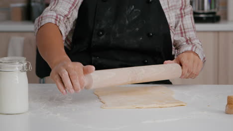 Closeup-of-child-hands-preparing-homemade-dough-using-rolling-pin