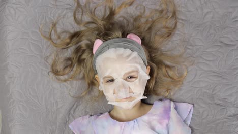 Teenager-Mädchen-Trägt-Feuchtigkeitsspendende-Gesichtsmaske-Auf.-Kind-Kümmert-Sich-Um-Die-Haut-Mit-Kosmetischer-Gesichtsmaske