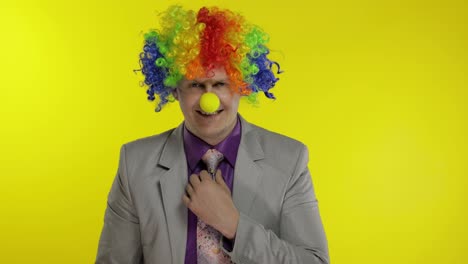 Clown-businessman-entrepreneur-boss-in-wig-adjusts-his-tie.-Yellow-background