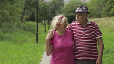 Senior-caucasian-couple-walking-in-park-embracing.-Elderly-man-walks-with-woman.-Husband,-wife