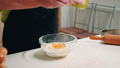 Close-up-of-hands-woman-adding-eggs-in-flour
