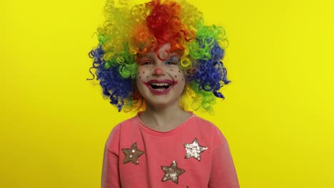 Little-child-girl-clown-in-rainbow-wig-making-silly-faces.-Having-fun,-smiling,-laughing.-Halloween